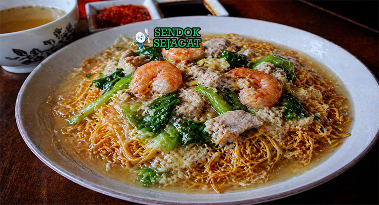 Mie goreng kering khas Makassar dengan tekstur renyah disiram kuah kental berwarna cokelat keemasan, berisi seafood dan sayuran segar