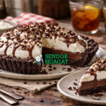 Mississippi Mud Pie khas Mississippi dengan lapisan cokelat lembut, crust Oreo renyah, dan topping whipped cream serta cokelat shavings disajikan di piring