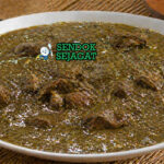 Sup berwarna hijau kecokelatan dengan potongan daging dan tekstur kental khas daun baobab