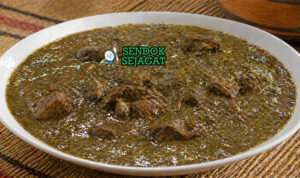 Sup berwarna hijau kecokelatan dengan potongan daging dan tekstur kental khas daun baobab