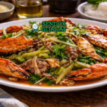 Mud crab with ginger and shallot khas Australia dengan potongan kepiting renyah, jahe iris, dan bawang merah harum disajikan di piring putih