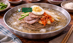 Mangkuk mul-naengmyeon khas Korea berisi mi kenyal di kuah dingin dengan irisan pir, timun, telur rebus, dan daging sapi tipis yang menggugah selera