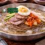 Mangkuk mul-naengmyeon khas Korea berisi mi kenyal di kuah dingin dengan irisan pir, timun, telur rebus, dan daging sapi tipis yang menggugah selera