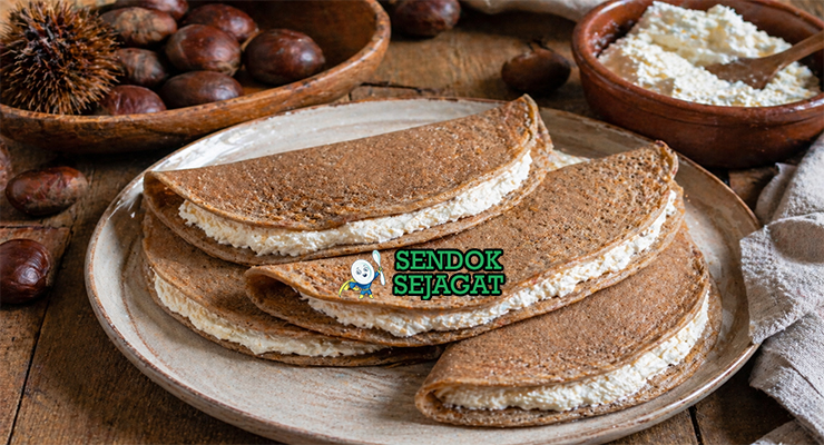 Pancake tipis berwarna cokelat dari tepung kastanye dengan isian ricotta putih lembut di atas piring rustic