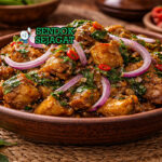 Hidangan nkwobi Nigeria autentik dengan potongan kaki sapi kenyal berbalut saus minyak sawit merah pedas, taburan daun utazi dan bawang bombay iris di mangkuk tradisional yang menggugah selera