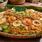 Pancit Malabon khas Filipina dengan mi tebal berwarna kuning jingga, ditaburi udang, cumi, telur rebus, chicharon, dan tinapa flakes disajikan di piring bambu