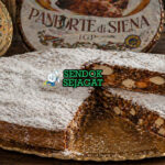 Kue panforte berbentuk bulat pipih dengan permukaan bertabur gula halus, terlihat padat berisi kacang dan buah kering dengan warna cokelat keemasan