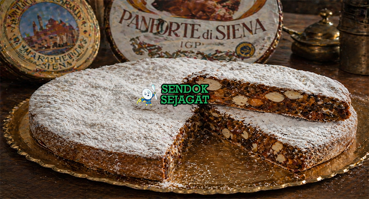 Kue panforte berbentuk bulat pipih dengan permukaan bertabur gula halus, terlihat padat berisi kacang dan buah kering dengan warna cokelat keemasan