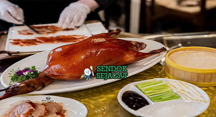 Peking duck khas Beijing dengan kulit cokelat keemasan mengkilap, tampak renyah dengan potongan tipis daging juicy, disajikan bersama pancake tipis, saus hoisin, dan irisan daun bawang