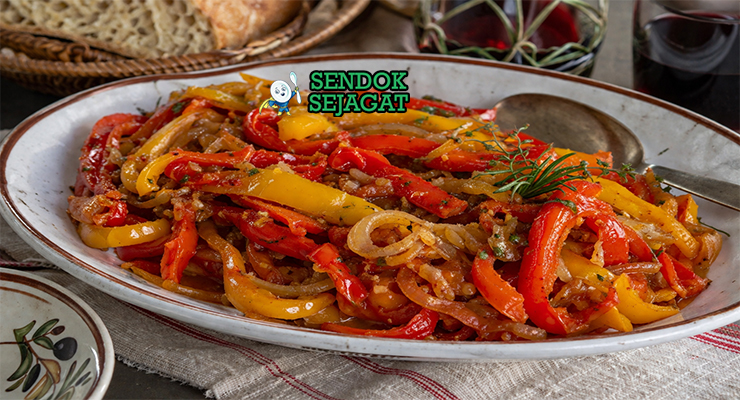 Peperonata khas Italia dengan potongan paprika merah, kuning, dan hijau yang tampak lembut dan mengilap, bercampur saus tomat ringan dan minyak zaitun dalam mangkuk rustic