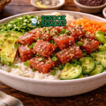 Mangkuk poke bowl khas Hawaii berisi nasi, potongan tuna segar marinasi, alpukat iris, edamame, mentimun, mangga, dan taburan wijen yang menggoda selera