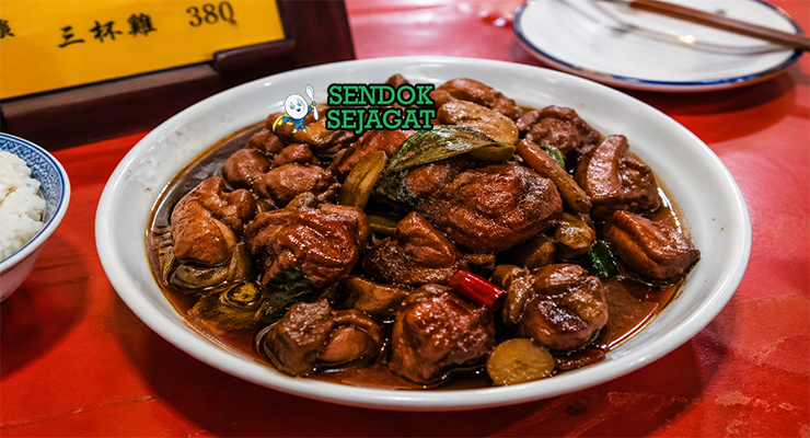 Potongan ayam berwarna cokelat gelap mengilap dengan saus kental, bawang putih, jahe, dan daun basil segar