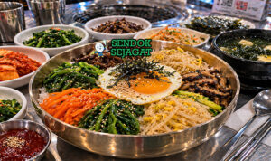 Mangkuk sanchae bibimbap khas Korea dengan nasi hangat, aneka sayuran gunung seperti bayam dan gosari, telur mata sapi, dan saus gochujang merah menggoda