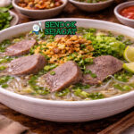 Sop lidah sapi khas Makassar dengan kuah bening, potongan lidah sapi empuk, bihun, dan taburan bawang goreng disajikan di mangkuk putih