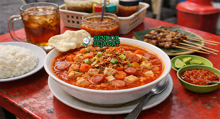 Sop merah khas Surabaya dengan kuah merah cerah, potongan ayam empuk, sosis iris, wortel, dan makaroni disajikan di mangkuk putih dengan bawang goreng tabur