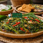 Stir-fried water spinach khas Asia Tenggara dengan kangkung hijau renyah dibalut bumbu cabai dan terasi, disajikan hangat di piring