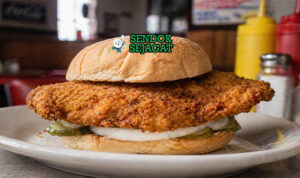 Sandwich dengan daging tenderloin goreng berukuran besar, roti bun, selada segar, dan saus creamy yang menggoda