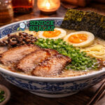 Tonkotsu ramen khas Jepang dengan kuah putih kental, mi tebal, chashu pork, telur setengah matang, nori, dan daun bawang disajikan di mangkuk hitam