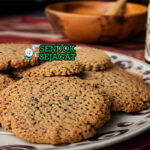 Biskuit wattleseed berwarna cokelat keemasan dengan tekstur renyah, tersusun di atas piring kayu dengan remah halus dan tampilan rustic