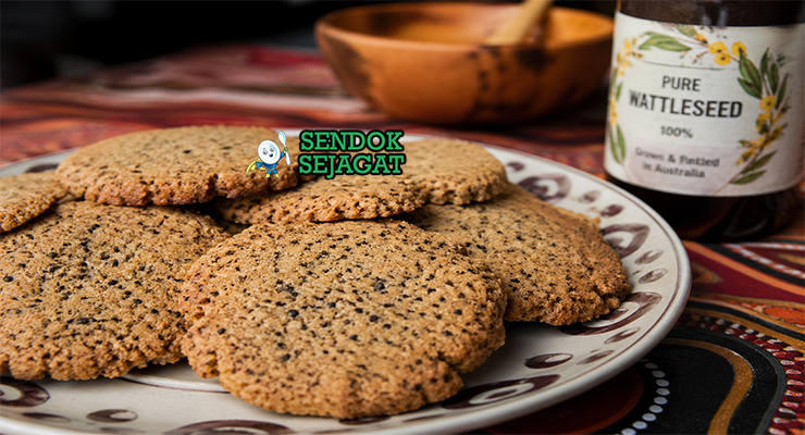 Biskuit wattleseed berwarna cokelat keemasan dengan tekstur renyah, tersusun di atas piring kayu dengan remah halus dan tampilan rustic